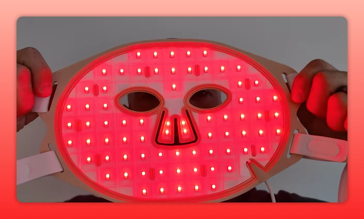 Close-up of a red light therapy LED face mask illuminated with multiple LEDs visible