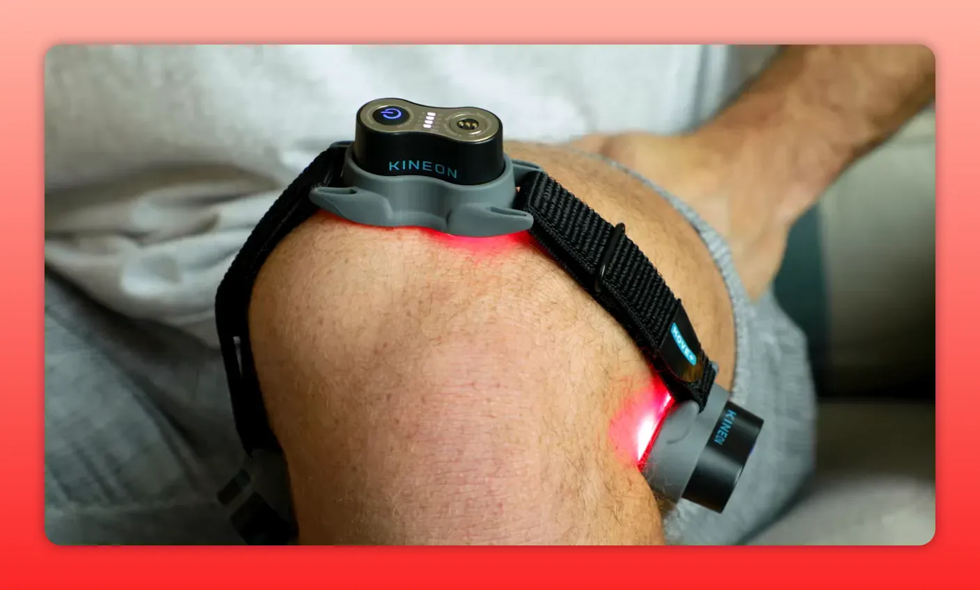 Close-up of a Kineon red light therapy device strapped to a person's knee emitting red light