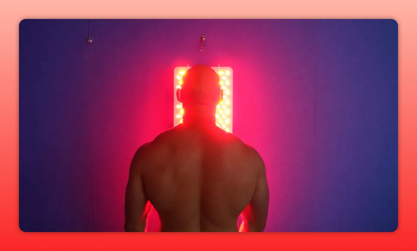 Rear view of a person standing in front of a vertical red LED panel with red glow on the upper back and shoulders