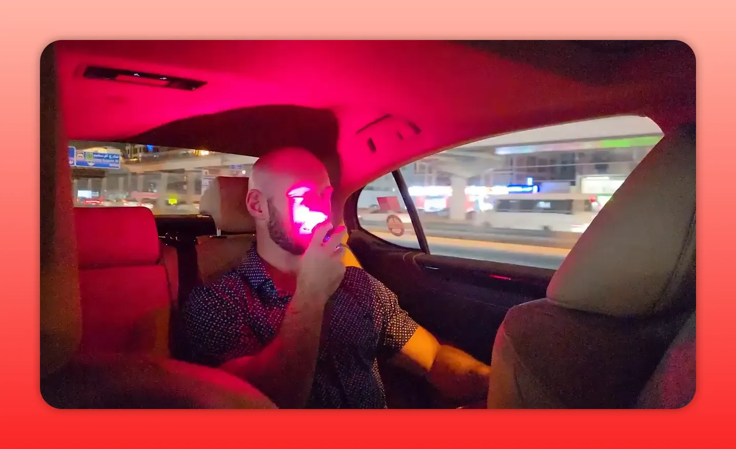 Person using a handheld red light therapy device on their face inside a car
