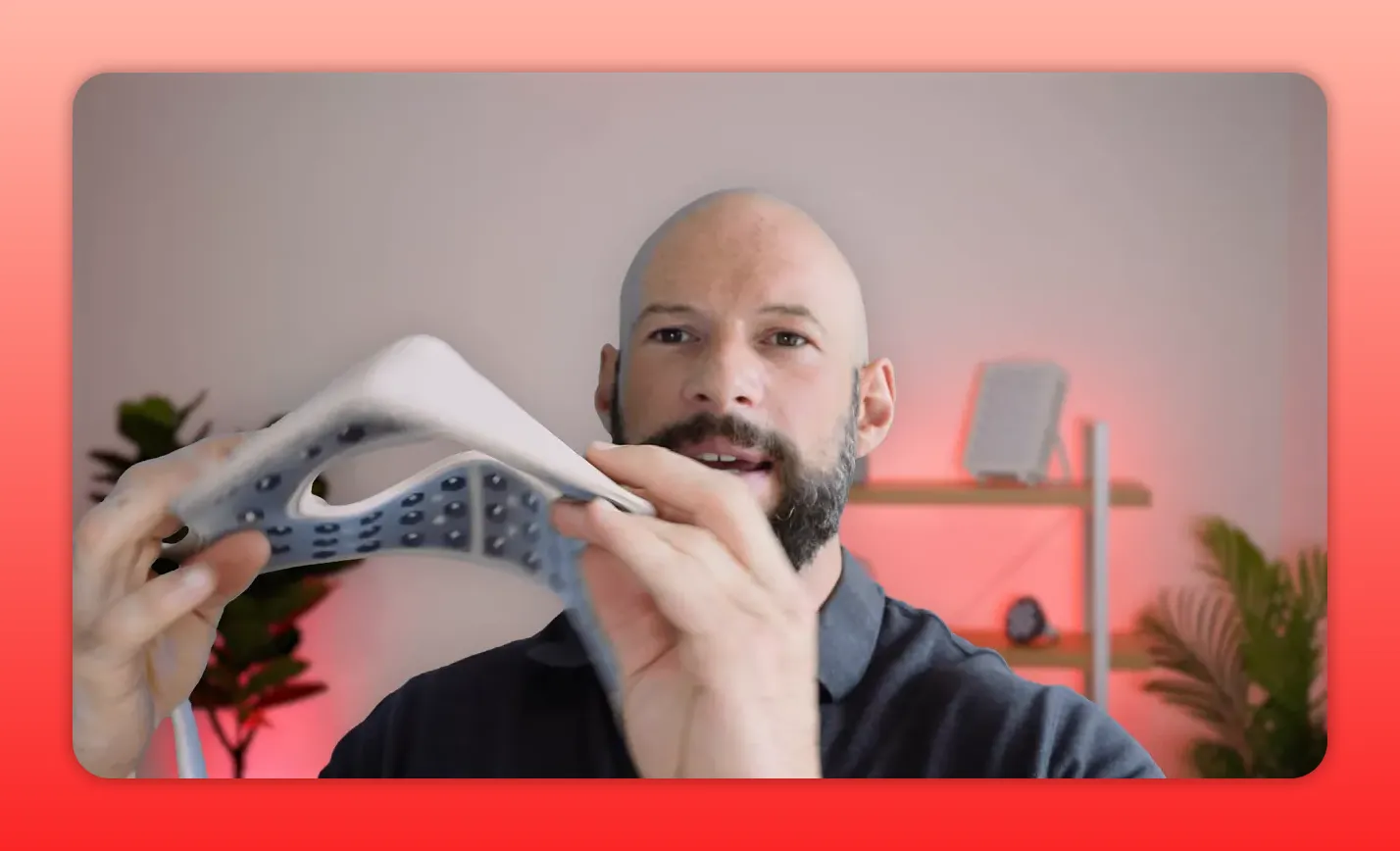 Hands flexing a semi-molded silicone red light therapy mask to demonstrate curvature and interior LED layout