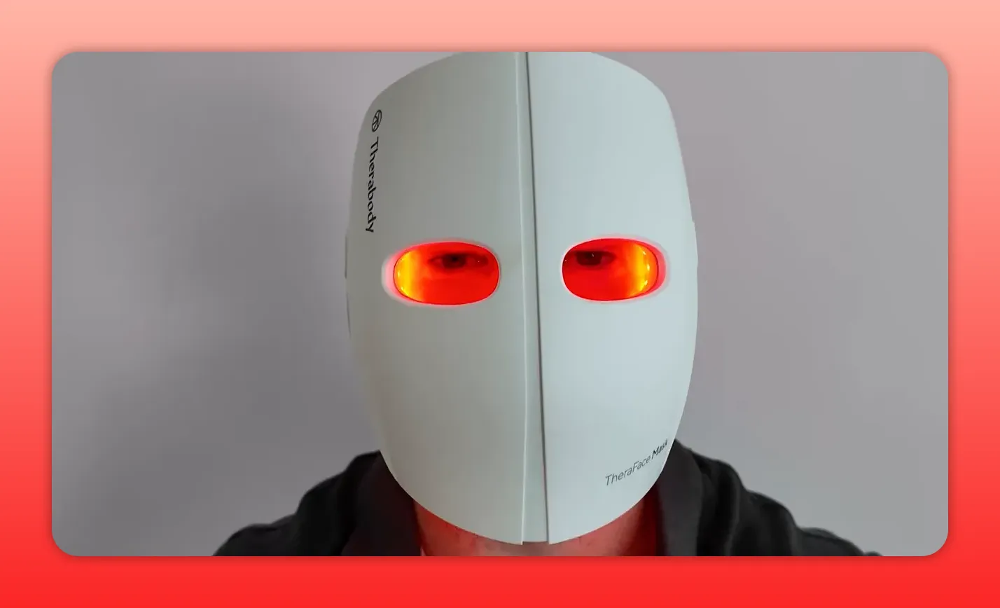 Centered front view of a rigid Theraface-style hard shell red light therapy mask with red LEDs showing through the eye apertures