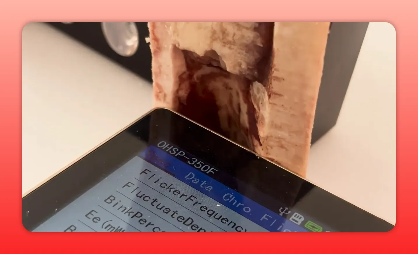 OHSP‑350F spectrometer display with a tibia cross‑section pressed against the sensor and the emitter in the background; text on the screen is readable.