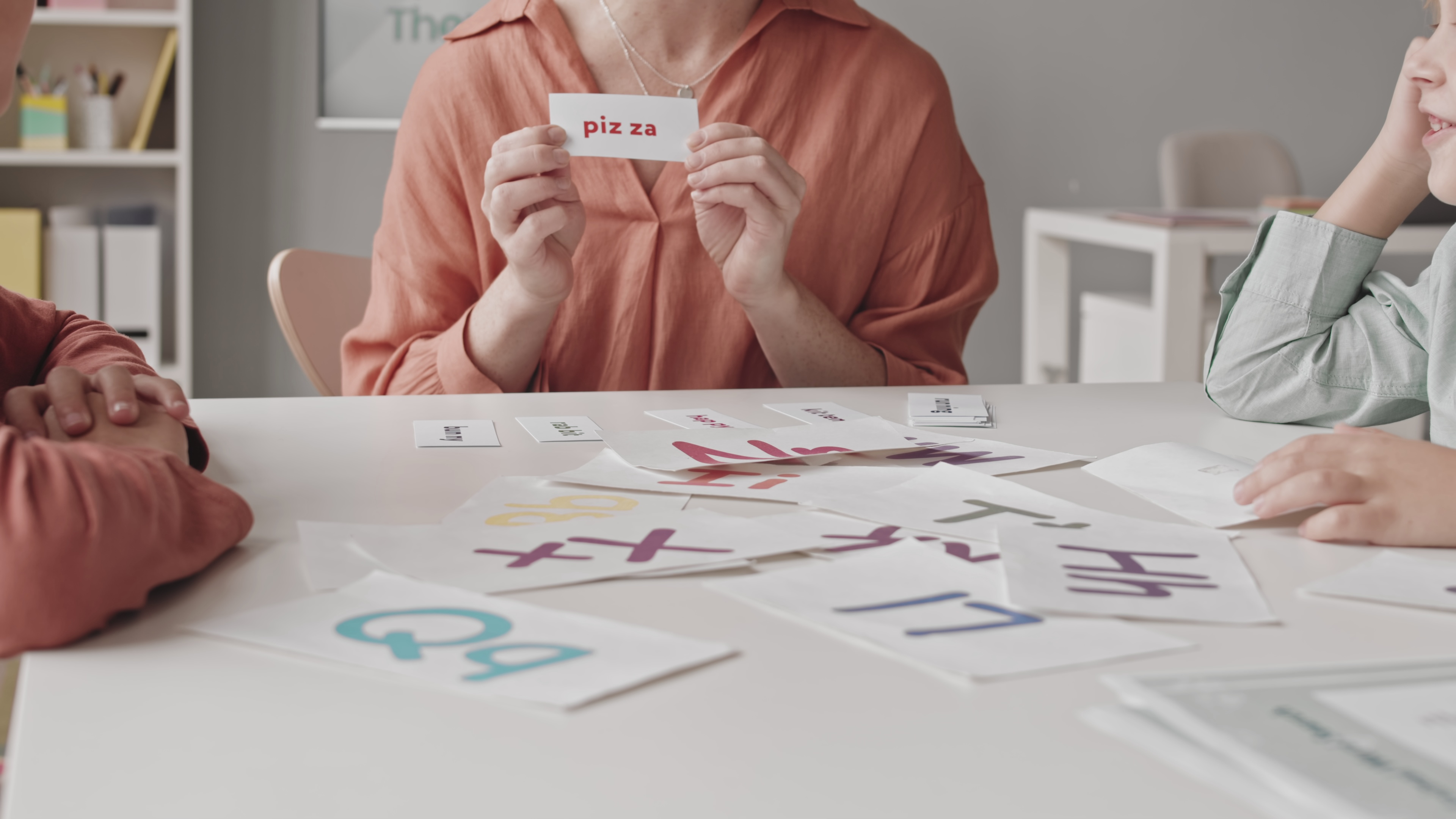 Two kids learning alphabet at speech therapy lesson with female teacher.
