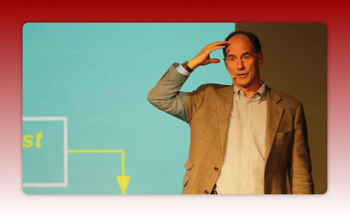 Speaker with hand on head mid-explanation next to a projected slide, clear and well-lit.