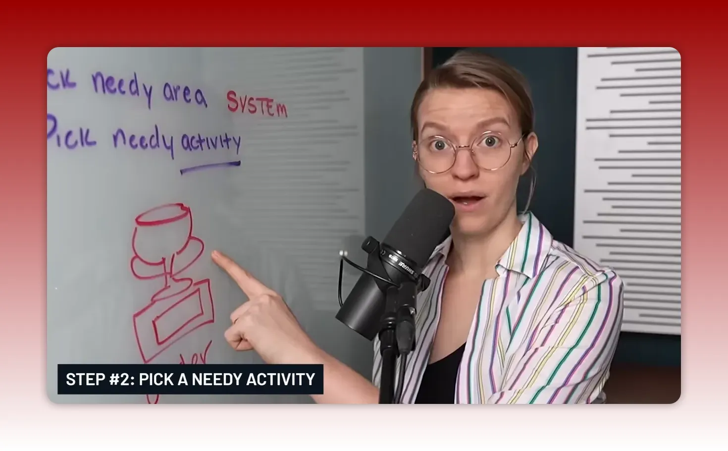 Presenter pointing at a whiteboard sketch while speaking into a microphone, highlighting 'Pick needy activity'