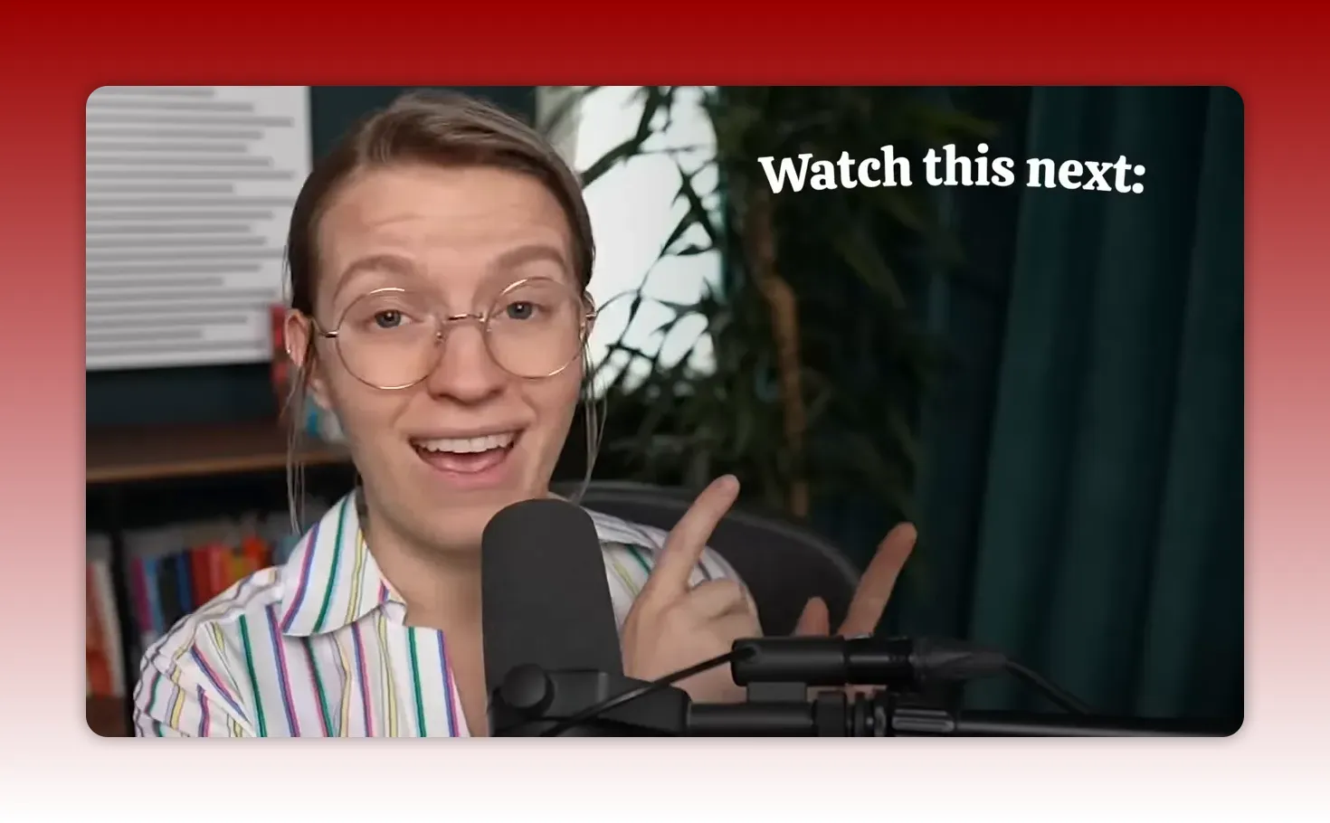 Person smiling and pointing to the right toward a visible 'Watch this next:' overlay, microphone and recording setup in foreground.