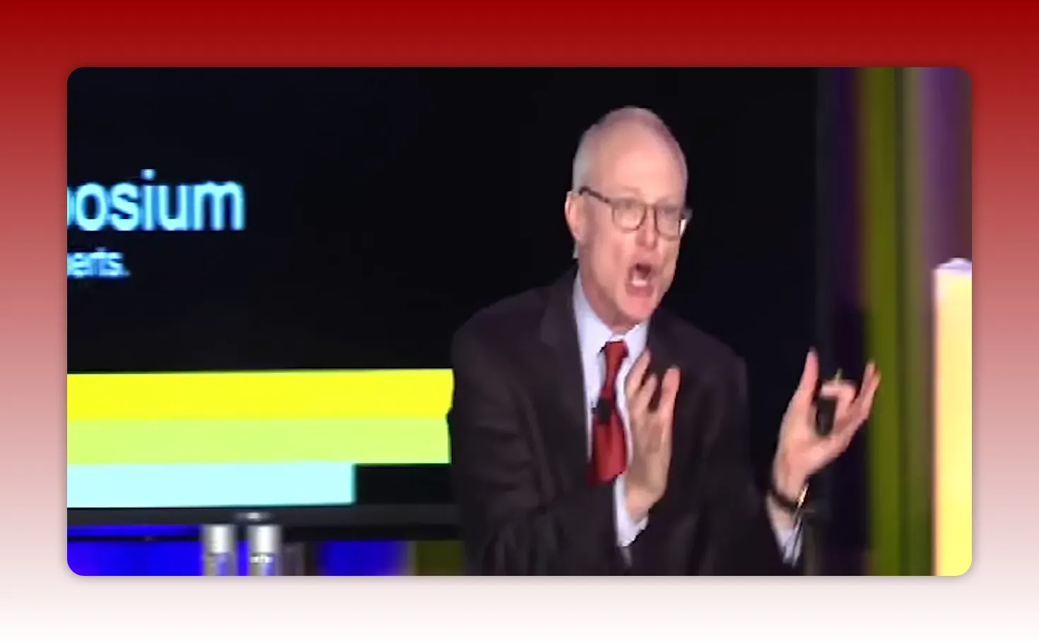 Presenter beside a screen showing a colored bar chart on a black slide, reinforcing the presentation content.