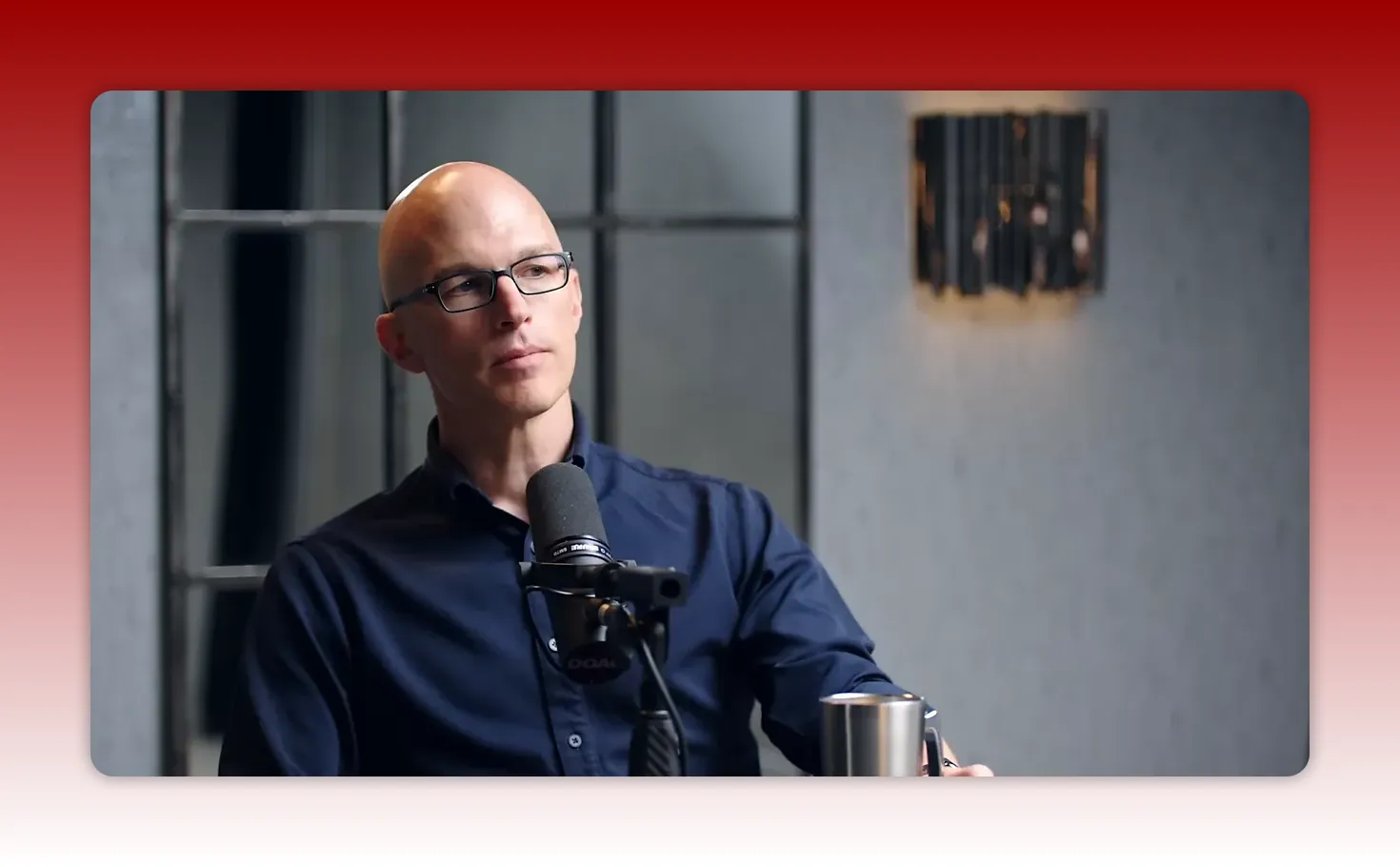 podcast speaker in navy shirt looking thoughtfully to the side while speaking into a microphone