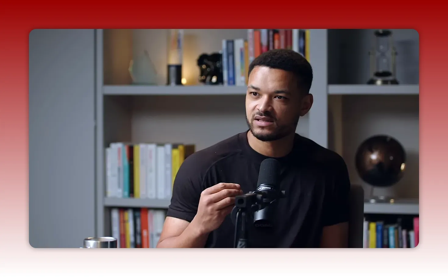 podcast speaker gesturing while speaking into a microphone with bookshelf in background