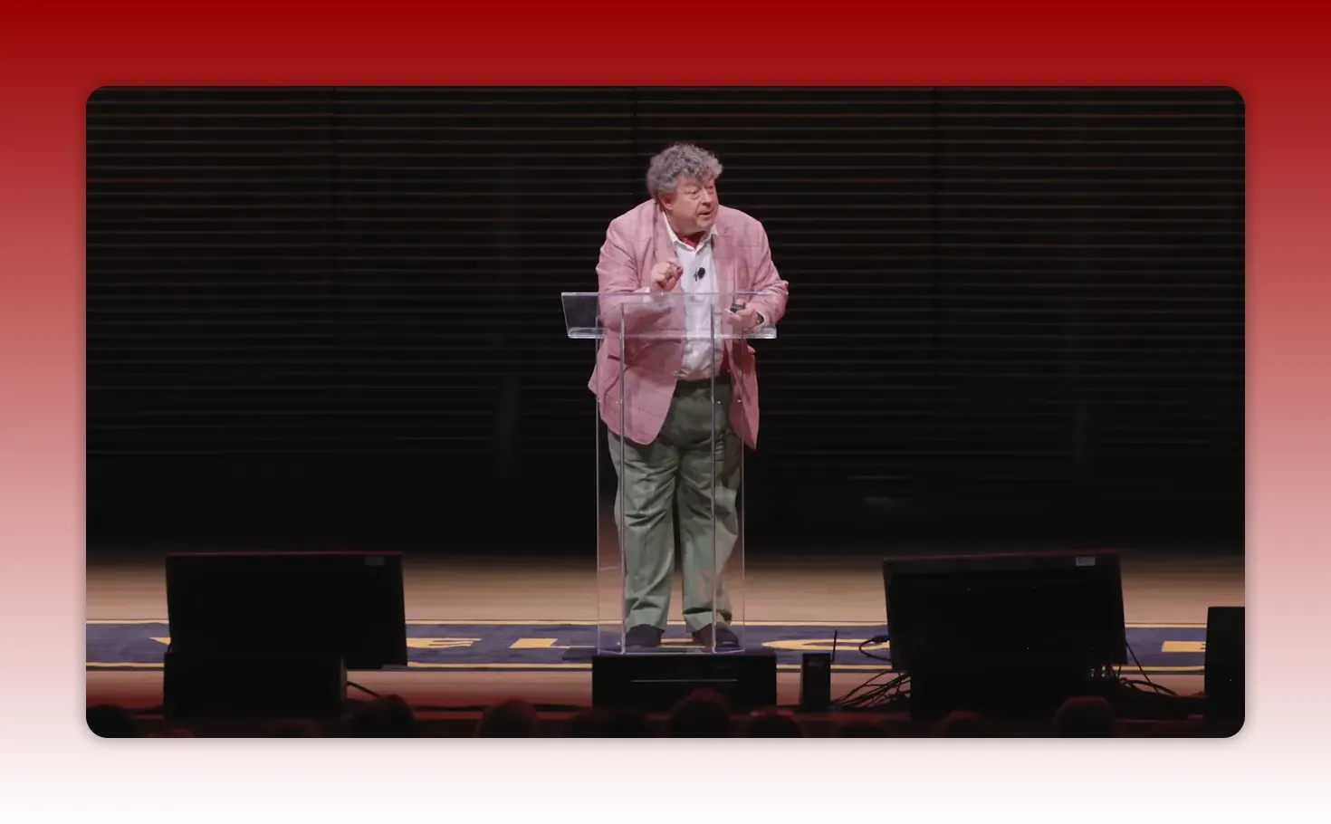 Clear, well-lit shot of a presenter at a transparent lectern gesturing while explaining two key rules