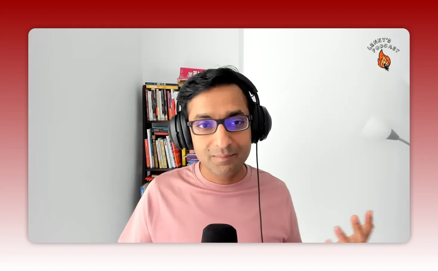 Clear head-and-shoulders shot of a podcast host with headphones and bookshelf behind, neutral expression.