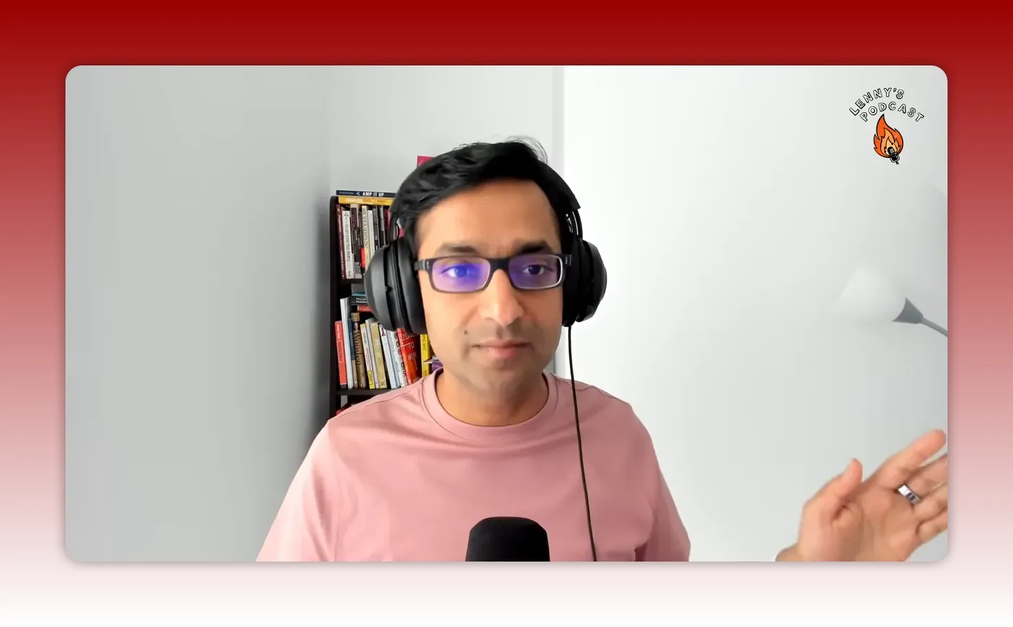 Clear head-and-shoulders shot of a podcast host wearing headphones, neutral engaged expression, bookshelf behind