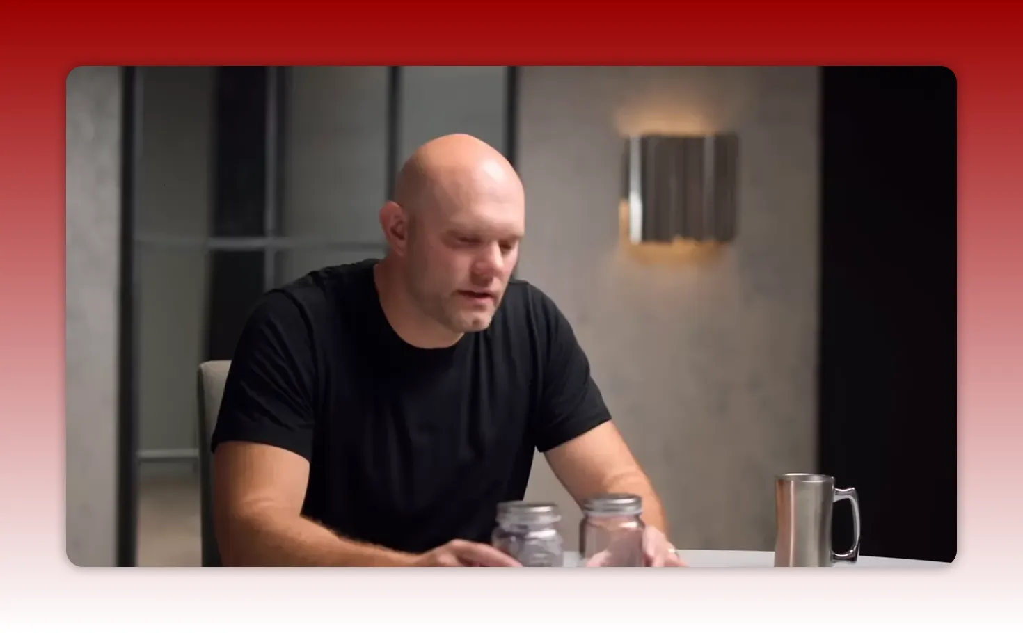 Presenter interacting with two glass jars and a metal mug on a table to demonstrate a physical habit tracker