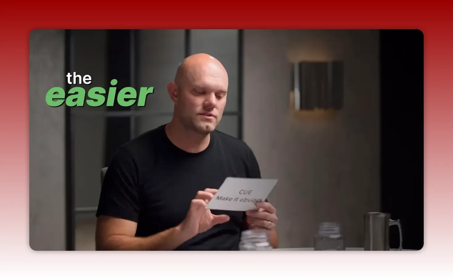 Speaker holding a card that reads 'CUE Make it obvious' in a discussion, clear and well-lit