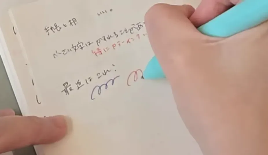 開いたノートの上に置かれたミントグリーンの多機能ペンと周辺の文房具