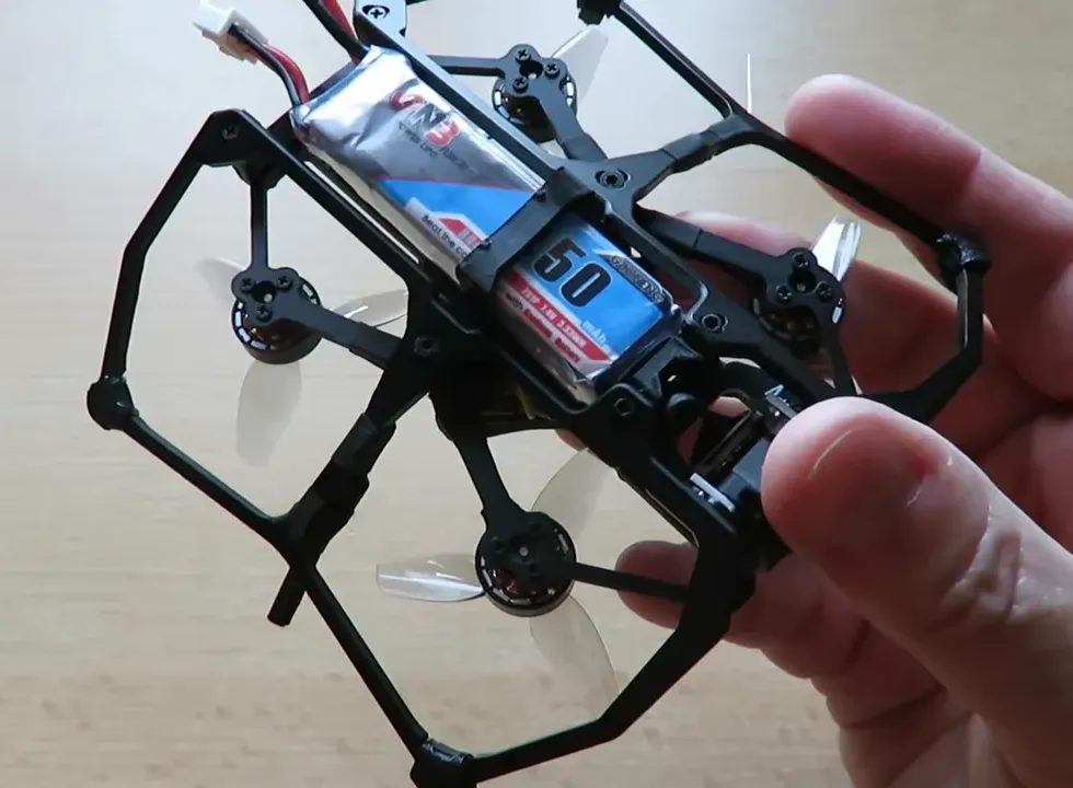 Carbonfly 80 pocket quad held in hand with a LiPo battery installed in the battery bay showing clearance and strap