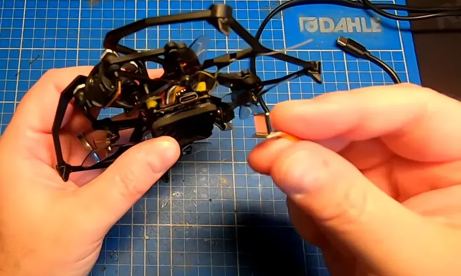 Carbonfly 80 held above a mat showing USB‑C port and O4 module with reviewer holding a small cable