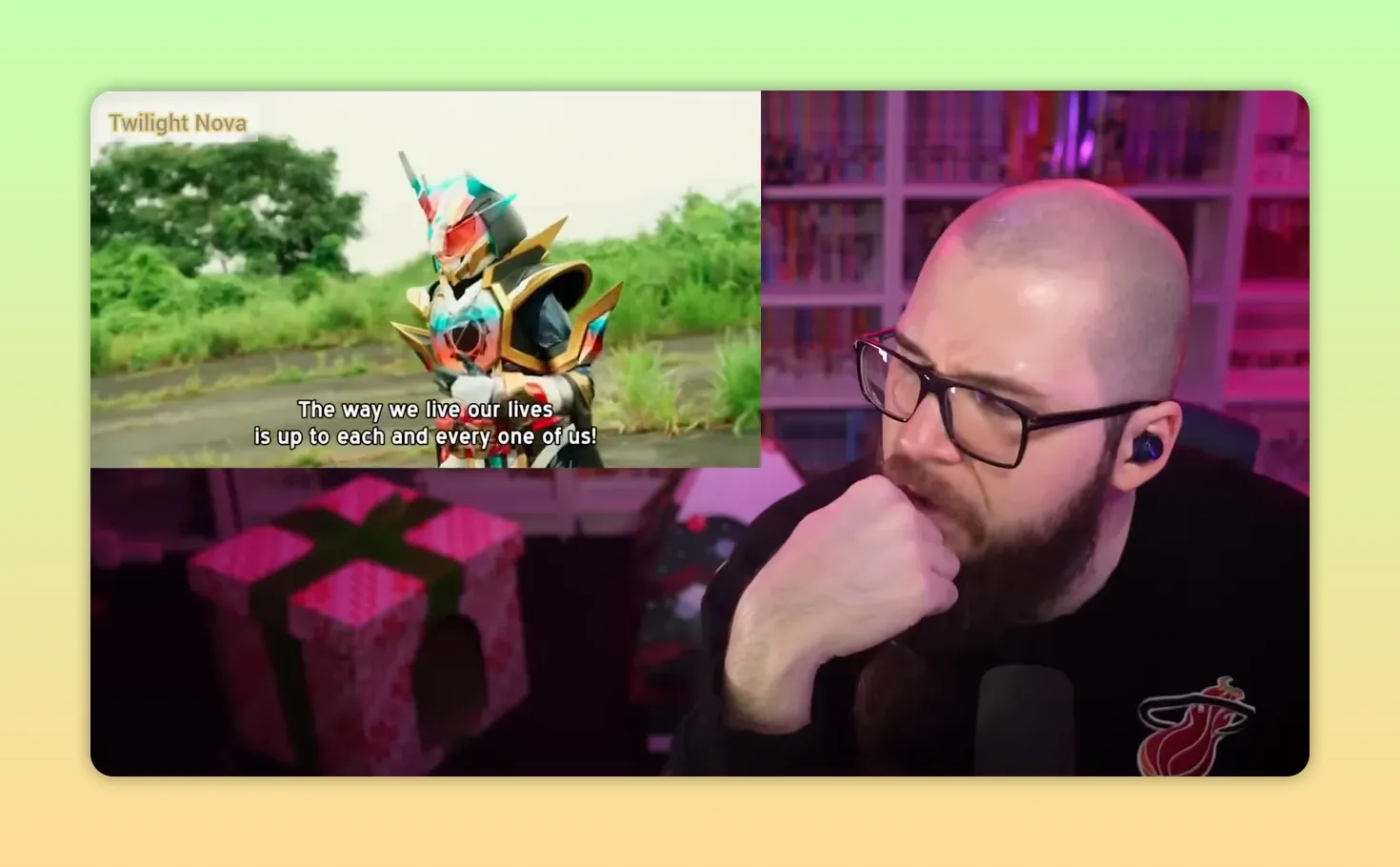 Full-frame shot of a female Kamen Rider-style final form in pinks, cyans and jewel-toned highlights standing outdoors with subtitles, streamer reacting at right