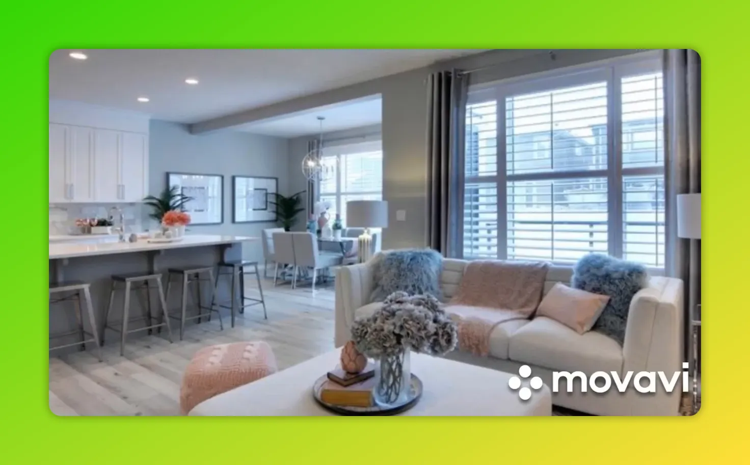 Open-concept kitchen and living room showing continuous light wood flooring, island with stools and a rug anchoring the seating area