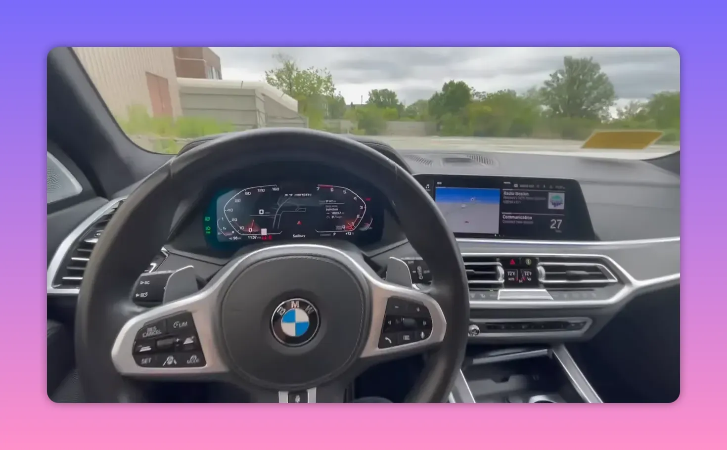 Clear driver's view of a BMW steering wheel, digital instrument cluster and center infotainment display