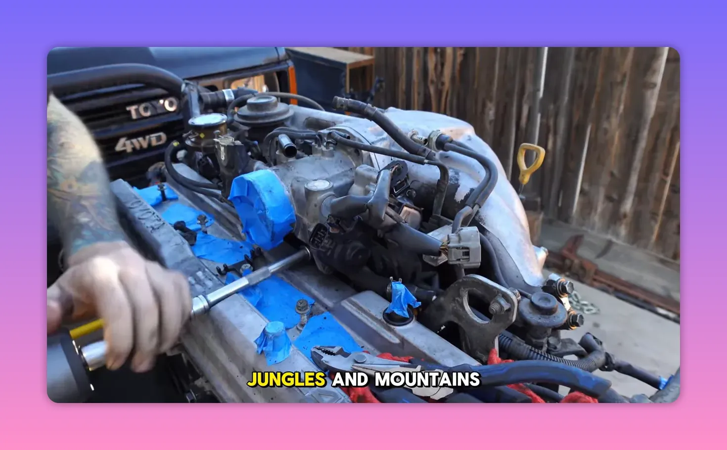 Top view of a Toyota 1FZ-FE inline-six engine with intake removed, ports taped and Toyota 4WD grille visible in background