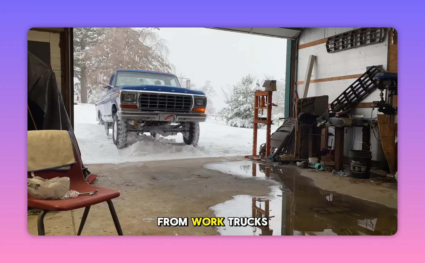 Front view of a blue vintage Ford pickup entering a garage with snow outside and reflections on the floor