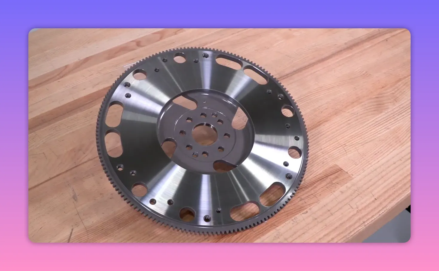 Angled view of a lightweight flywheel on a wooden workbench showing cutouts and teeth