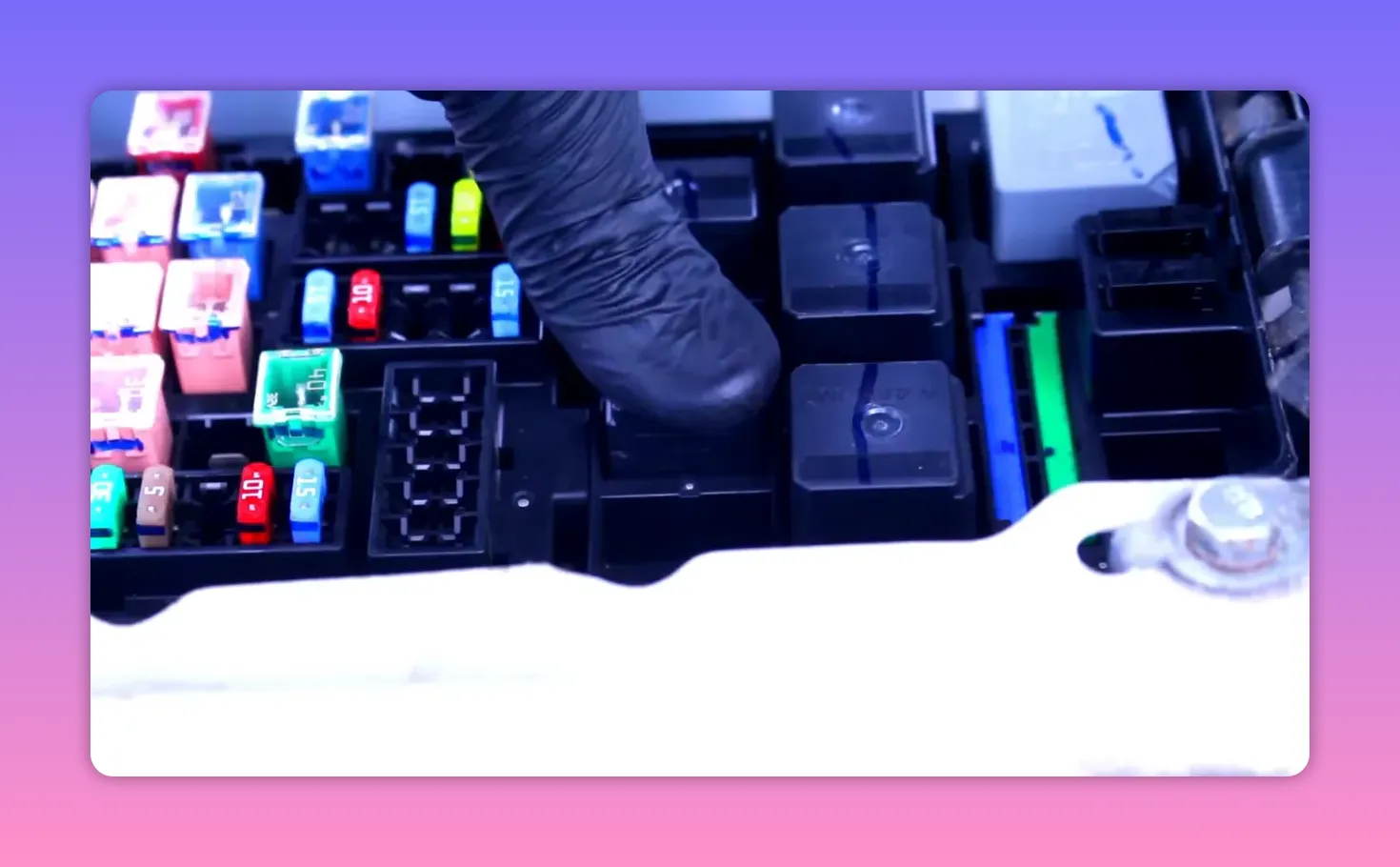 Gloved finger pointing at a relay slot and surrounding fuses in a car's under‑hood fuse box.