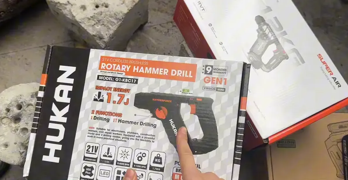 Hộp Hukan rotary hammer drill, logo và thông số rõ ràng, ngón tay chỉ vào hộp
