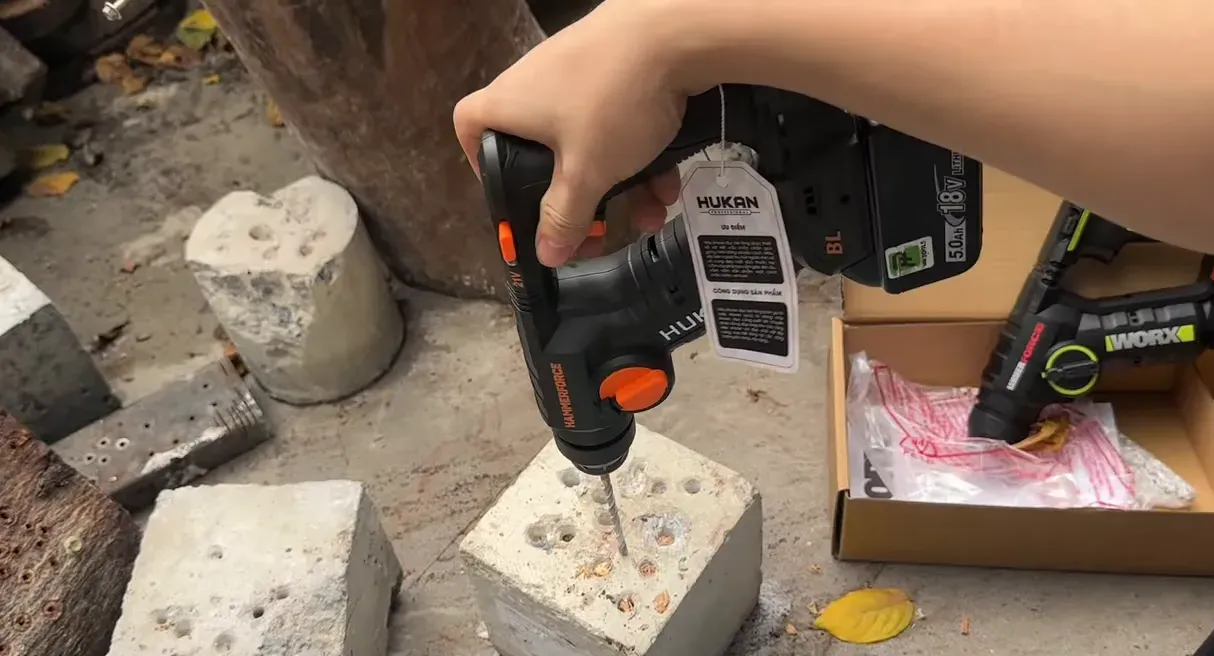 Hukan khoan bê tông mũi nhỏ, mũi khoan chạm vào khối bê tông với nhiều lỗ đã khoan