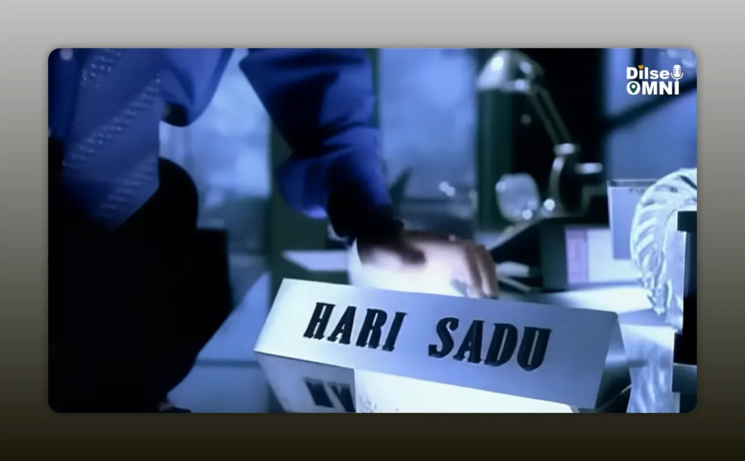 Desk nameplate reading Hari Sadu next to office phone on a table