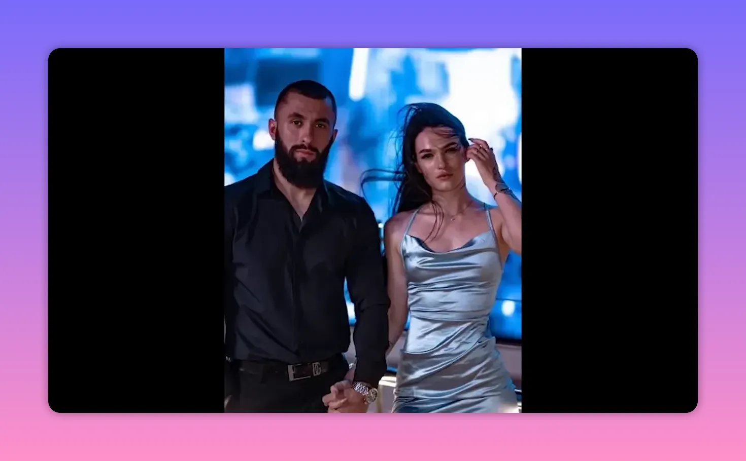 A man and woman standing together dressed formally, posing hand-in-hand in low evening light