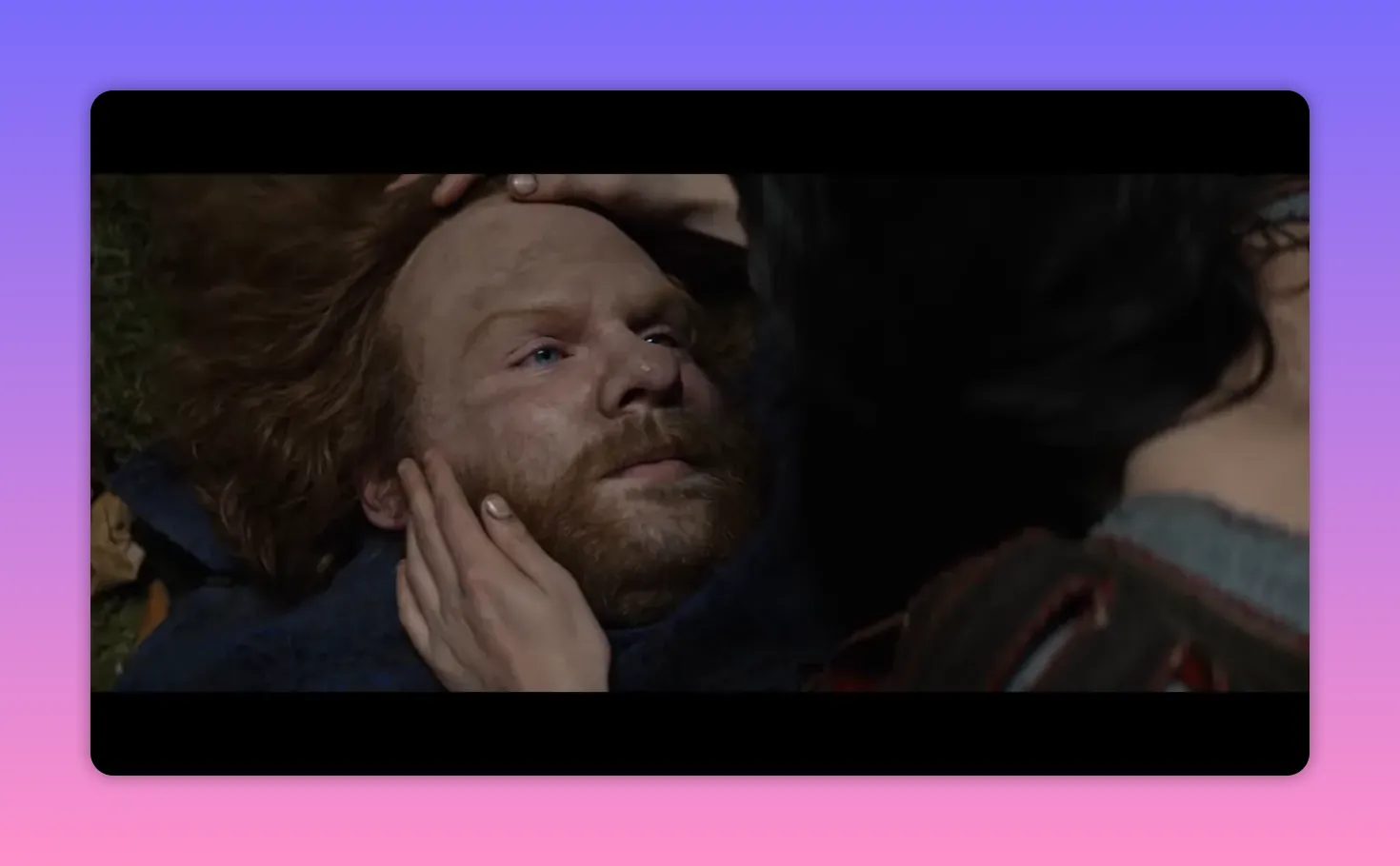 Injured bearded man lying on the ground, a woman&rsquo;s hands on his head and cheek as she tends him