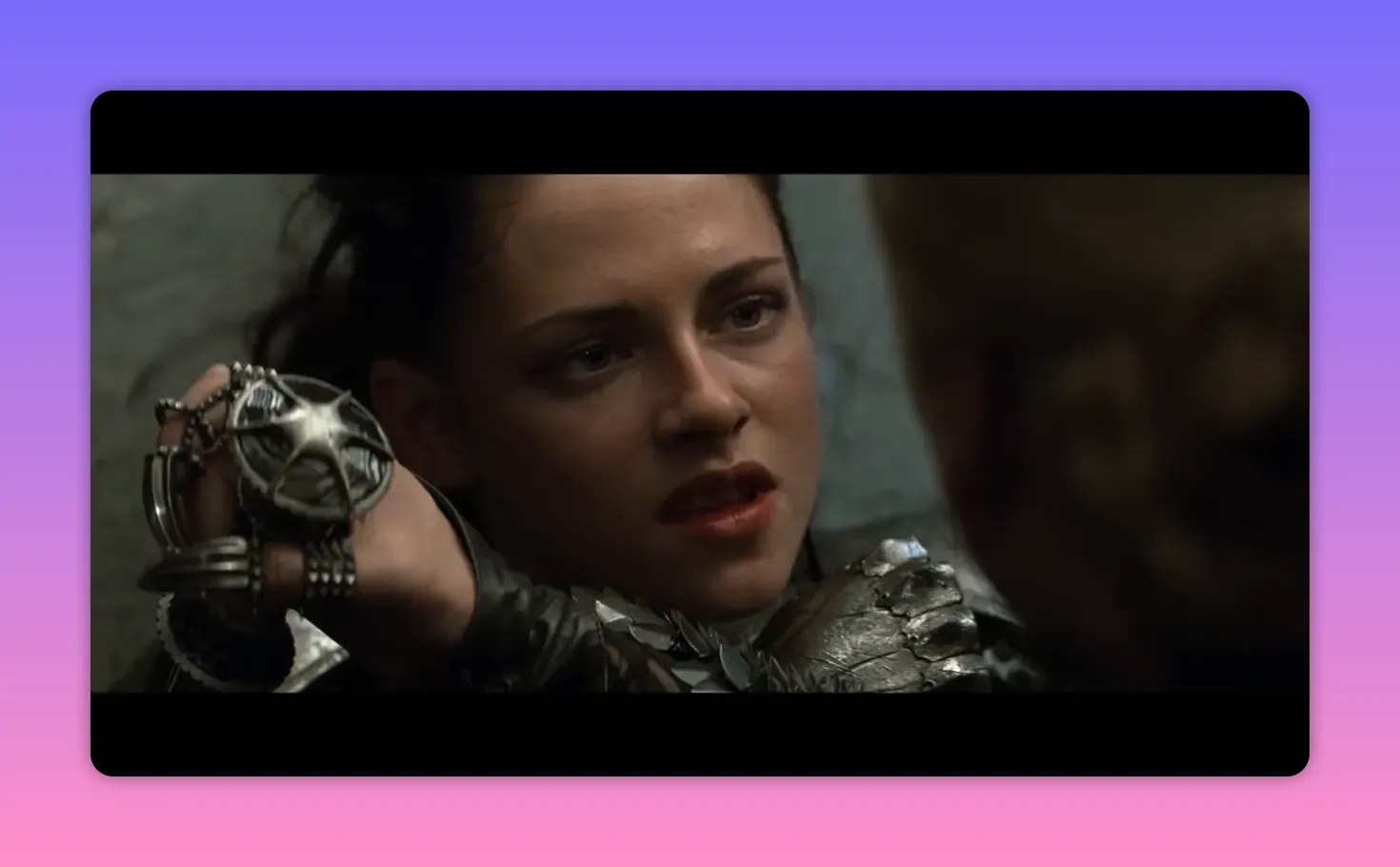 Close-up of a young warrior pressing a star-shaped pendant at an opponent's throat, face tense.