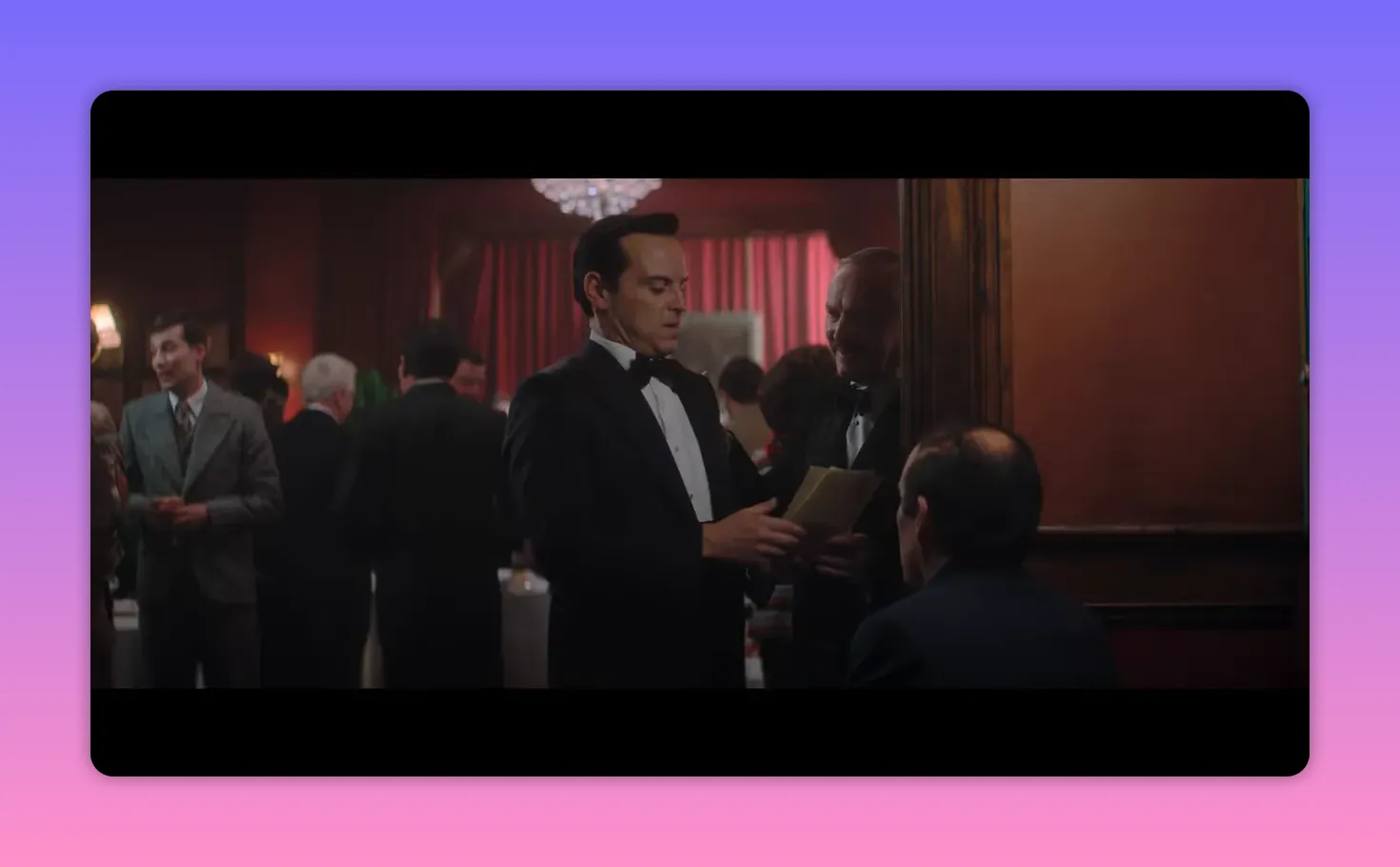 man in tuxedo handing papers to another man at a crowded reception