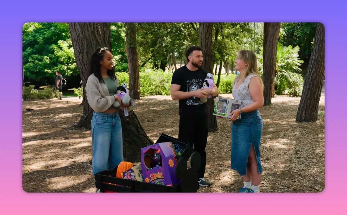 Wide shot of the prize cart full of Disney-themed items with the host and two contestants standing nearby in a park.