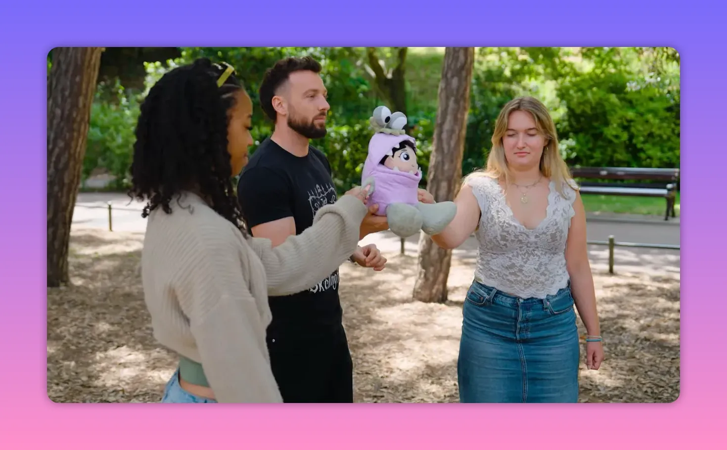 Two contestants with eyes closed each holding an arm of a purple Boo plush doll while the host stands between them.