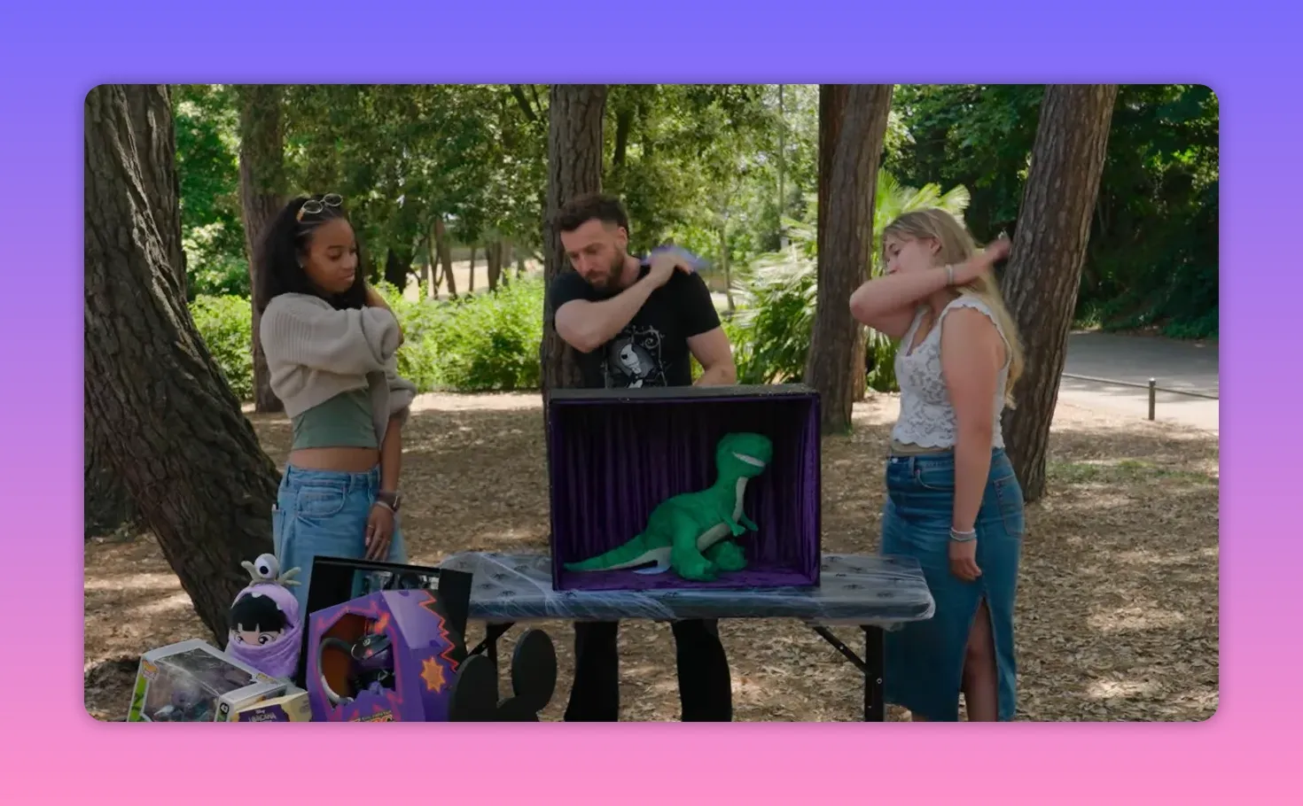 Outdoor game table with a covered box containing a plush prop and two players listening to the host
