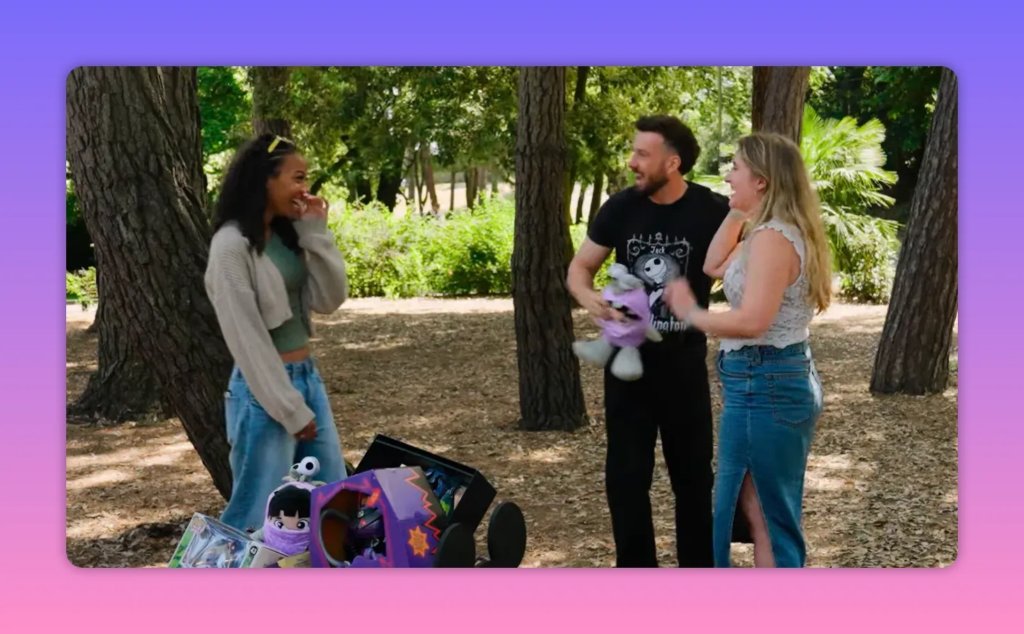Host and two contestants laughing beside a red prize cart filled with Disney-themed items and plush toys in a park.