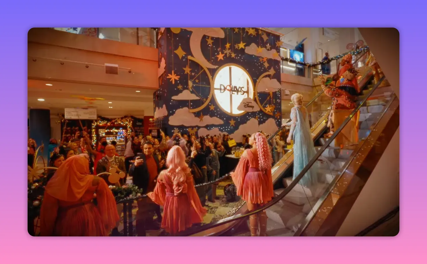 Audience watching costumed performers on an escalator in front of a large decorated Disney-themed wall at Selfridges