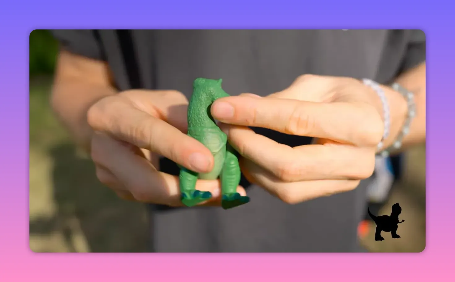 close-up of hands holding a small green toy dinosaur prop