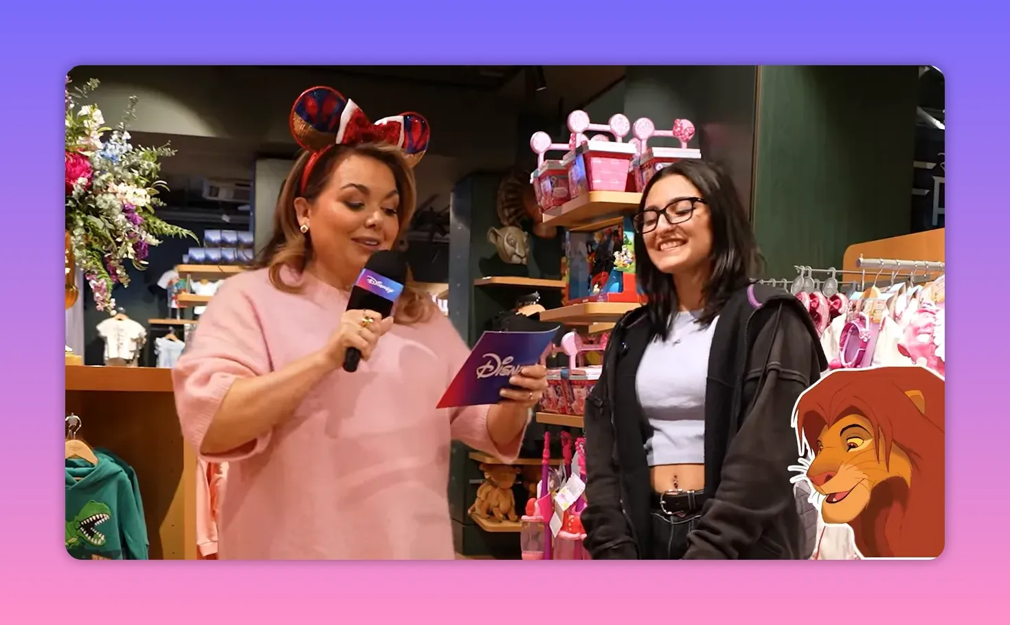 presenter reading a question card into a microphone while a guest smiles in a Disney Store