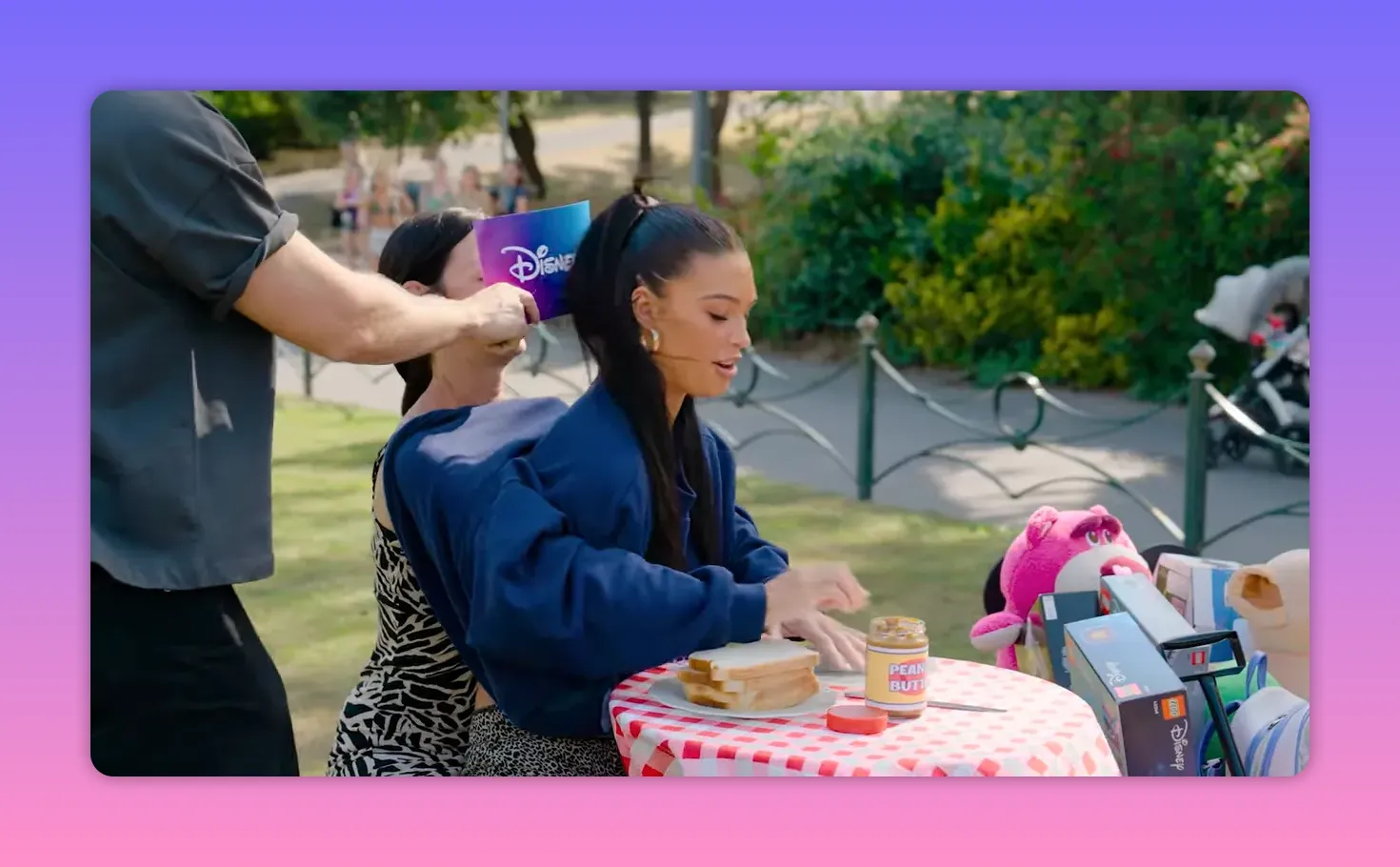 Volunteer being blindfolded at the start of the blindfolded sandwich challenge with peanut butter jar on a red‑checkered table
