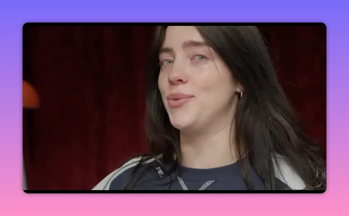 Close-up of performer with teary eyes looking slightly off-camera, indoor red background