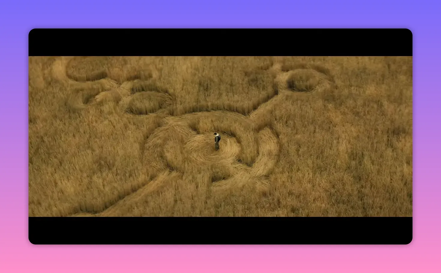 Aerial shot of an intricate crop circle in a golden field with a person standing in the central circle