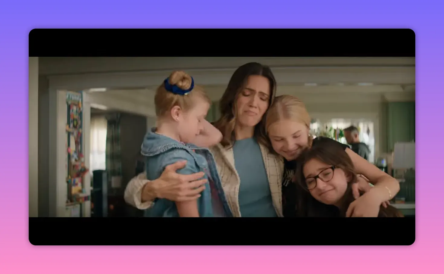 Parent embracing three smiling children in a warm kitchen hug