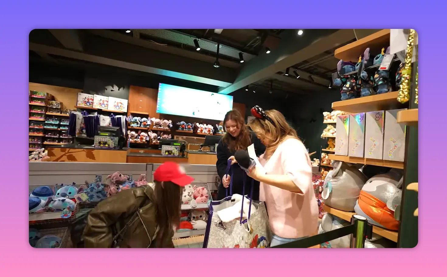 Interior view of a Disney Store showing the host and participants beside a stanchion marking the activity area with plush displays behind
