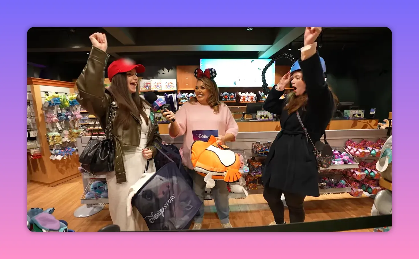 Host holding a Nemo plush while two participants cheer and celebrate inside a Disney Store