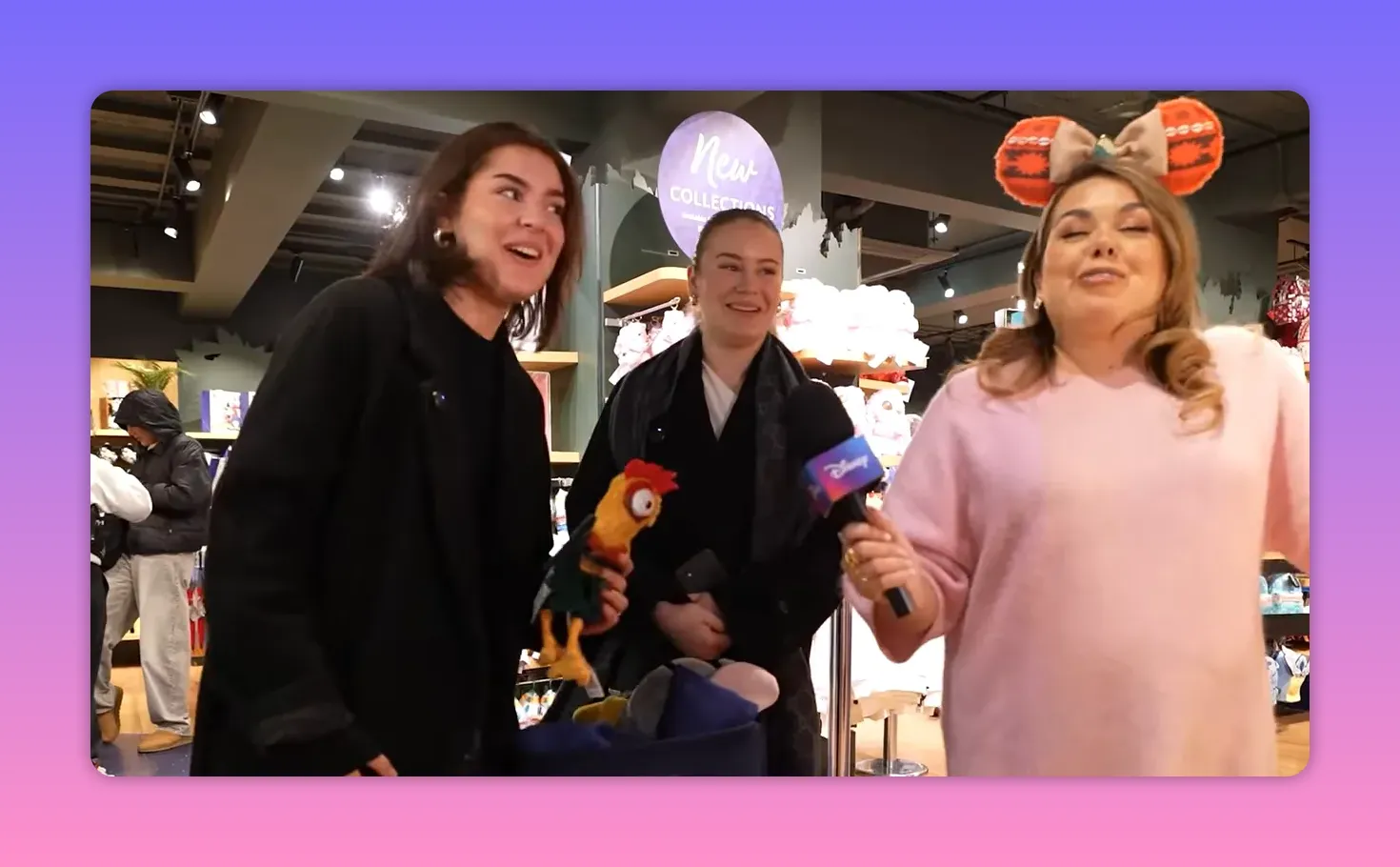 Three people laughing together in a Disney store while the host holds a microphone; bright, candid reaction shot.